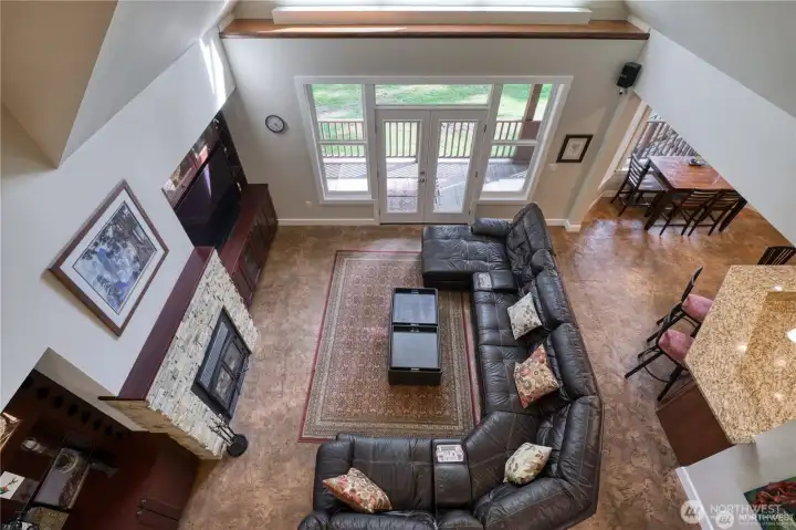 View of the living room from the second level bridge, French doors leading to the backyard deck and patio.