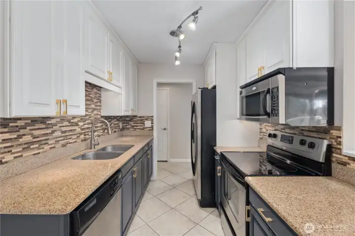 Kitchen View: Efficient kitchen layout with sleek stainless steel range, microwave, and refrigerator. The design maximizes counter space and offers easy flow into the dining and living areas.