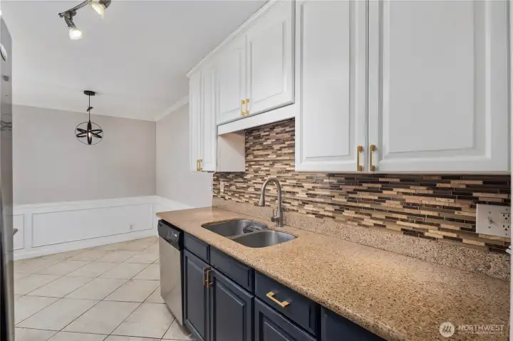 Kitchen: Galley-style kitchen with granite countertops, stainless steel appliances, and abundant cabinet storage. Modern backsplash, tile flooring, and under-cabinet lighting create a stylish and functional cooking space.
