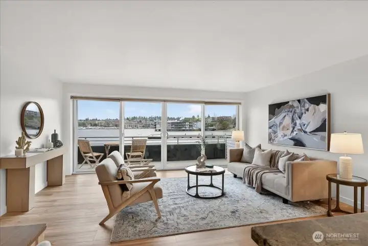 Walls of glass bring Lake Washington directly into the living room — panoramic north-facing views of the marina, open water, and David E. Brink Park stretch beyond the sliding doors leading to your private deck, all bathed in natural Pacific Northwest light.
