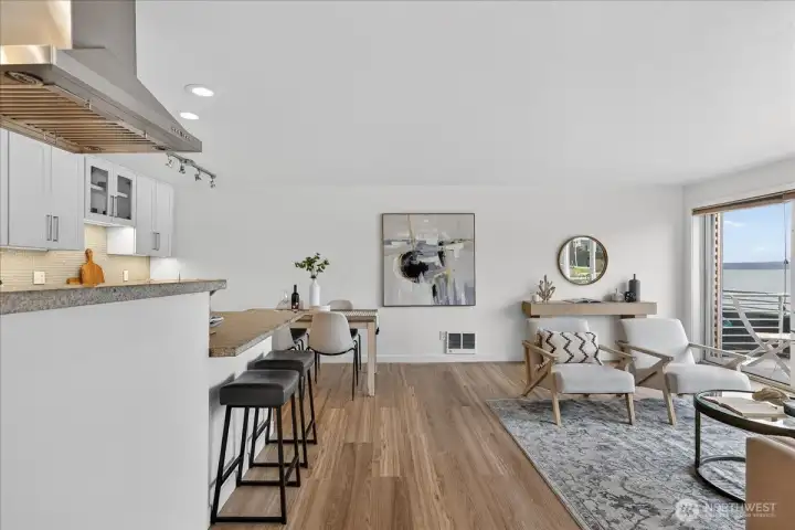 One sweeping space — kitchen, dining, and living flow effortlessly together, with warm floors and Lake Washington framed in the sliding glass doors.