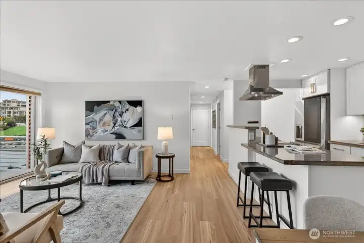Open-concept living and kitchen with hardwood floors, granite counters, stainless steel range hood, and breakfast bar — all just steps from your private deck overlooking Lake Washington