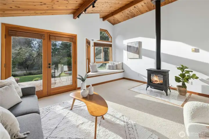 The main living room with a cozy propane fireplace, french doors out to the western facing deck and a cozy sunny window seat.