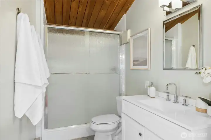 The connected primary bathroom with an over-sized shower, updated flooring and fixtures.