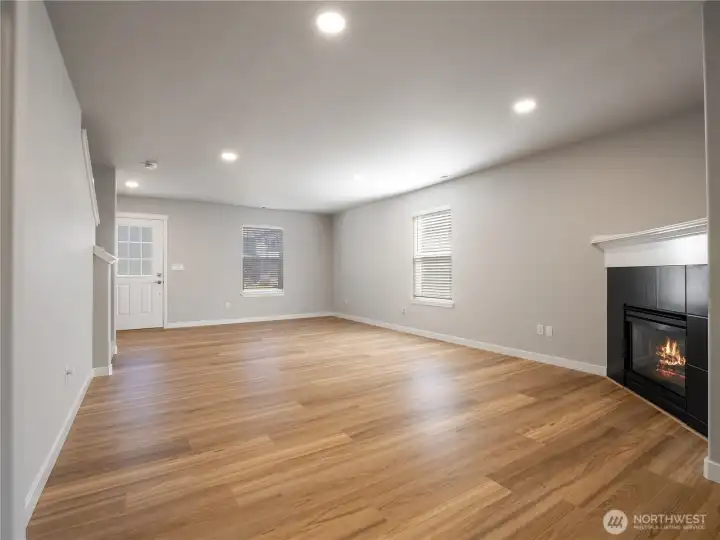 The inviting living room features a cozy gas fireplace and added lighting that fills the space with warmth and natural brightness.