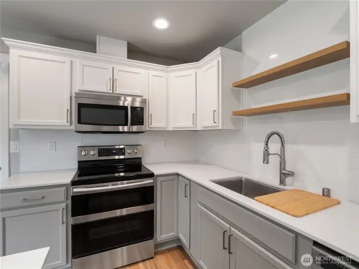 Light, airy tones were chosen for the kitchen remodel, complemented by brand new wood shelving and a fresh sink to create a bright and inviting space.