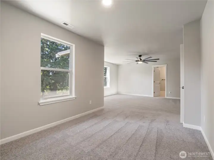 The primary suite showcases multiple windows allowing for an abundance of natural light and an open, airy ambiance.