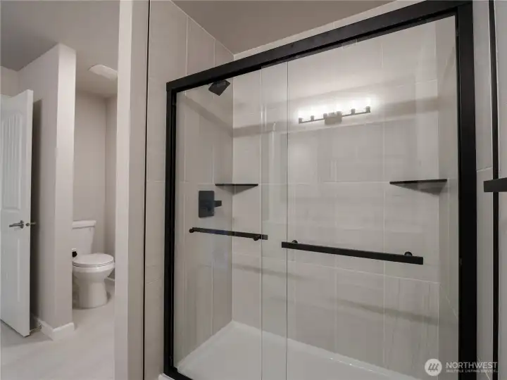 A brand-new, sleek shower showcases modern finishes and black-outlined glass doors for a clean, elevated look.