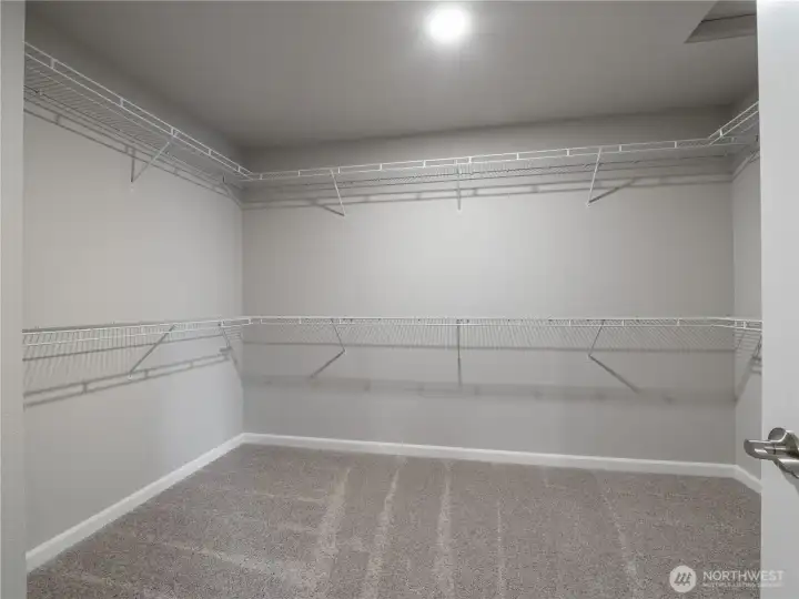 The massive walk-in closet features two hanging racks and shelving for optimal storage and organization.