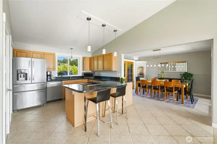 Kitchen with vaulted ceilings, eating area, dining room and window view of back yard, corner gas fireplace