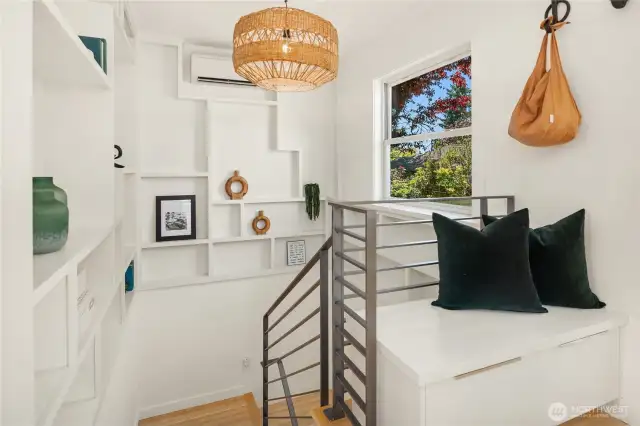 The wrap around shelving unit is a work of art that looks over the welded steel railing. One of the mini-splits is part of the design providing warmth in the winter and A/C in the summer. An entry bench with pull out storage is off to the right.
