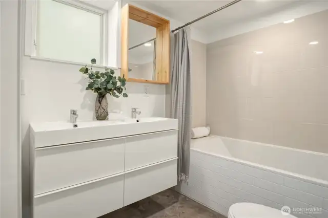 A second full bath located downstairs with a tiled bath and oversized floating vanity.