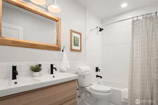 The oversized full bath features a dual sink vanity and a tiled tub surround.