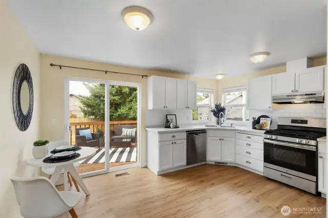 Bright and open kitchen features white cabinets, subway tle backsplash and slider to sunny deck.