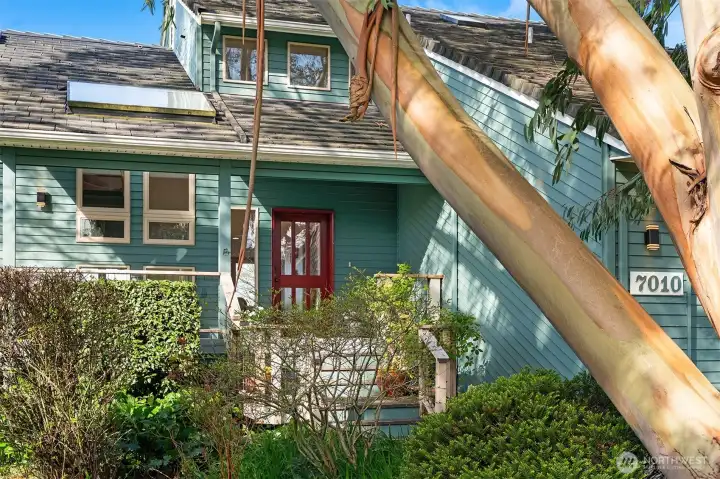 Charming entry with inviting front porch, lush greenery, and architectural character.