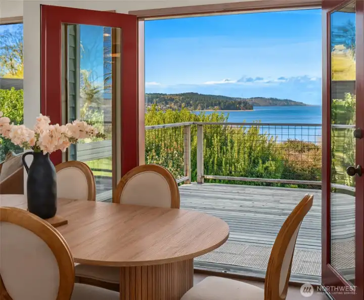 Dining area with expansive windows and direct access to the deck, capturing stunning water views.