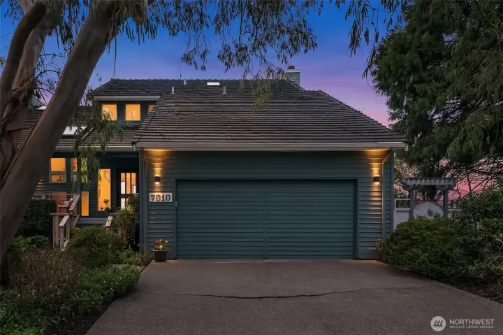 Twilight exterior of garage and entry, highlighting warm lighting and inviting curb appeal.