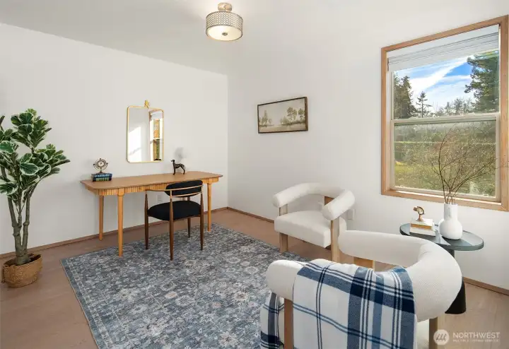 Light-filled office or flex space with large window and comfortable layout for work or relaxation.