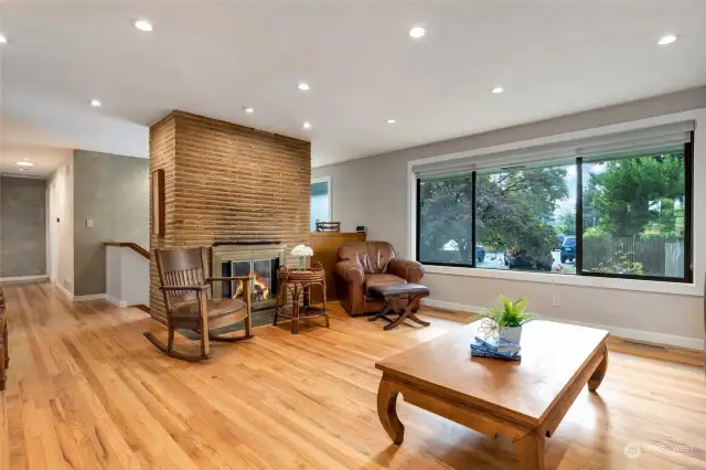 Wood Burning fireplace adorns one wall of the living room. Hardwood floors extend down the hallway of the home.