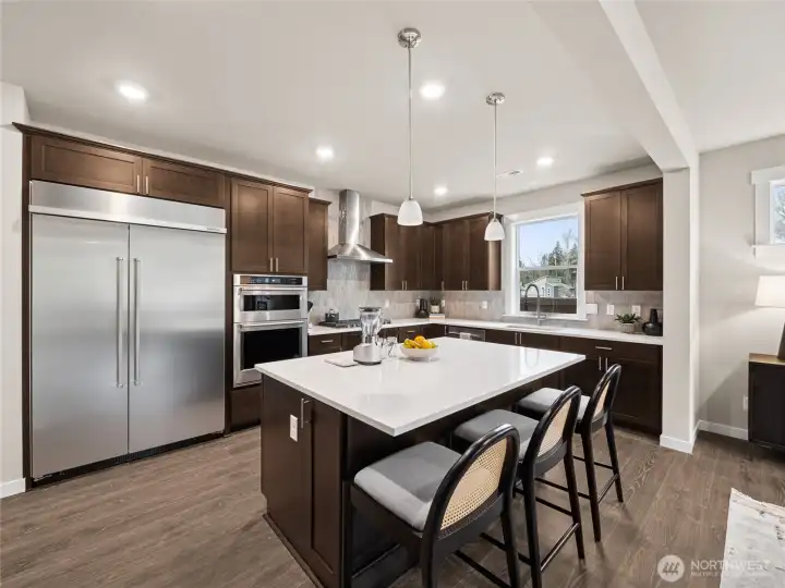 Gourmet kitchen with large center island, quartz counters, real wood cabinets with soft close hinges, gas cooking, and built-in 48" fridge. Photo is representational. Actual home is under construction and finishes and paint colors may vary. See site agent for details.... Gourmet kitchen with large center island, quartz counters, real wood cabinets with soft close hinges, gas cooking, and built-in 48" fridge. Photo is representational. Actual home is under construction and finishes and paint colors may vary. See site agent for details....