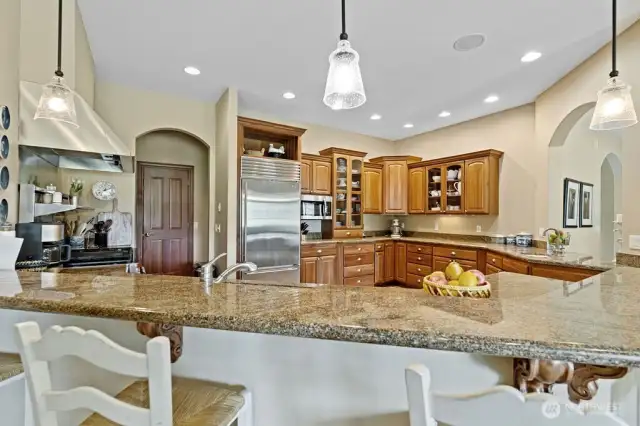 The gourmet kitchen featuring Dacor gas range, Sub-Zero refrigerator, quartz countertop and commercial grade kitchen hood. There are plenty of cabinets, counter space and this generous eating area.