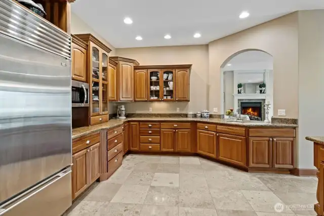 From the gourmet kitchen in this open concept living home, one of the Ledge Stone and granite fireplaces burns brightly.