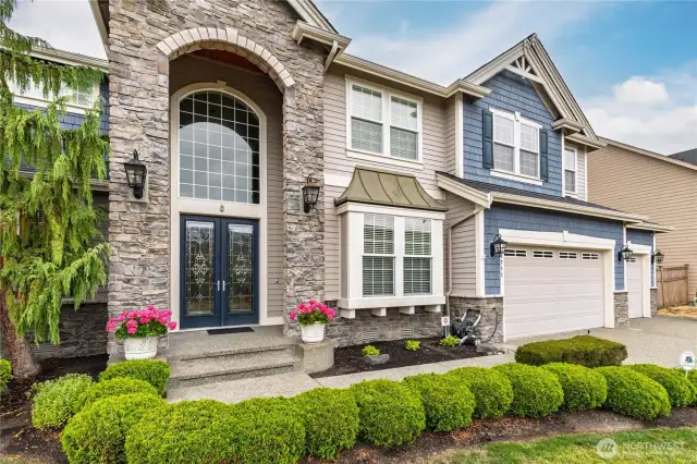 Grand 2-story stone-covered entry with double glass doors