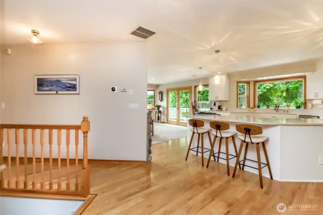 Step into a bright and welcoming entry that immediately showcases the home's desirable open floor plan. Gleaming hardwood floors extend throughout, reflecting abundant natural light. From the entryway, a clear sightline draws you towards the spacious kitchen, featuring a large island with seating – perfect for casual gatherings.