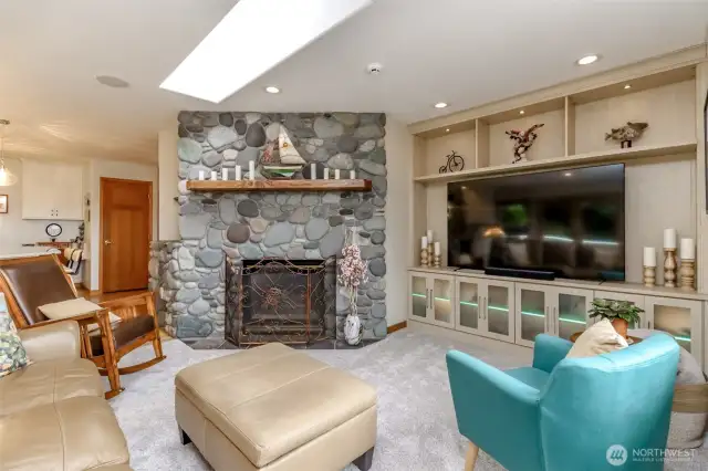 This elegant living room centers around a striking stone gas fireplace, creating a warm and inviting focal point. The custom built-in entertainment center offers ample storage and seamlessly integrates a large television, perfect for modern living.