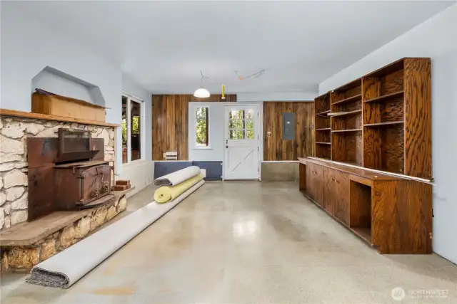 Lower-level great room with wood stove & free-standing shelving, new roll of carpe & pad for lower-level bonus room, buyer to install. Exterior door
