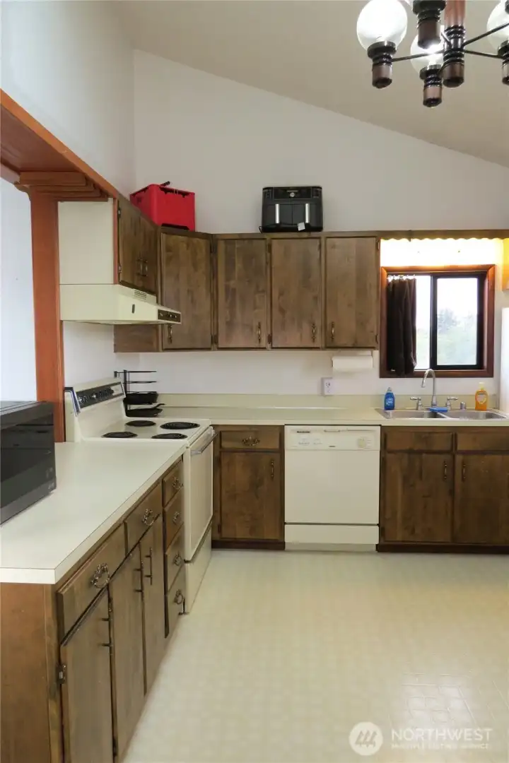THE KITCHEN ALSO HAS VAULTED CEILINGS AS WELL AS PLENTY OF CABINETS!  THIS VIEW SHOWS THE RANGE AND DISHWASHER!