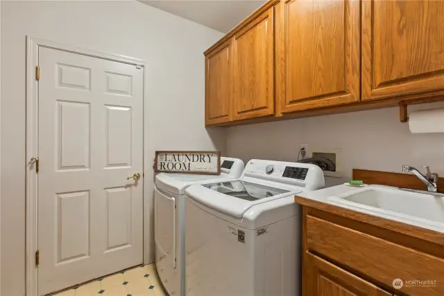 Laundry with utility sink, access to the garage, a closet, and another wall of cabinets of the opposite side.