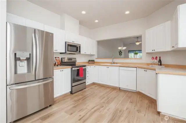 Generous kitchen with crisp white cabinetry and newer fridge, stove & microwave