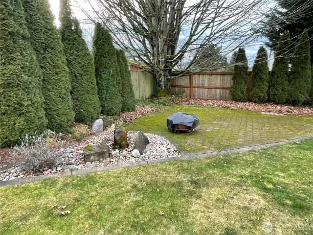 This back corner of the property is a stone fire pit area that includes a cute water feature in that front rock landscaping.