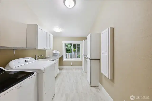 Generous upstairs utility room with built-in ironing board, space to hang clothing and folding station.