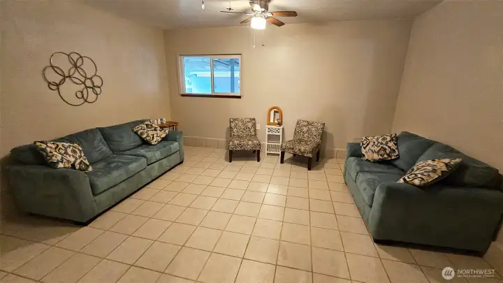 A large extra finished room with tile flooring and two ceiling fans. This room is conveniently off of the family room, has its own exterior entrance door, and is ready for multi-purpose use.