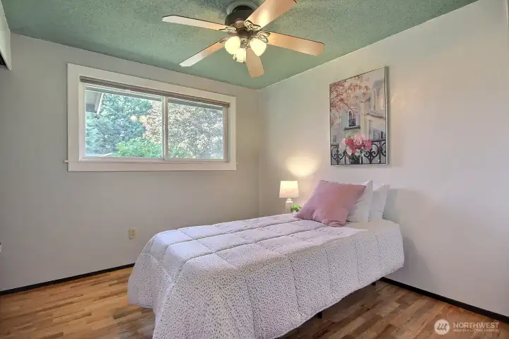 Guest bedroom #1- A bright and inviting space with beautiful hardwood floors, plenty of natural light, and a ceiling fan for added comfort.