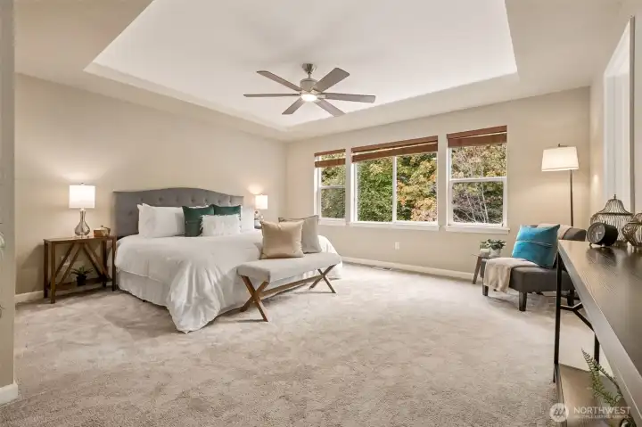 The primary bedroom with its ceiling fan and tray ceiling.