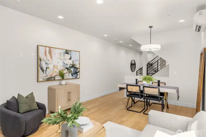 An open-concept dining area transitions seamlessly between the kitchen and living room, highlighted by sleek modern lighting