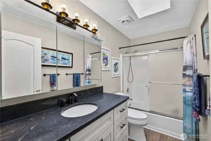 This is the second Bathroom with a new Quartz Countertop, LVP flooring, new light and plumbing fixtures.  It has a Large Skylight and is located next door to the second Guest Bedroom.
