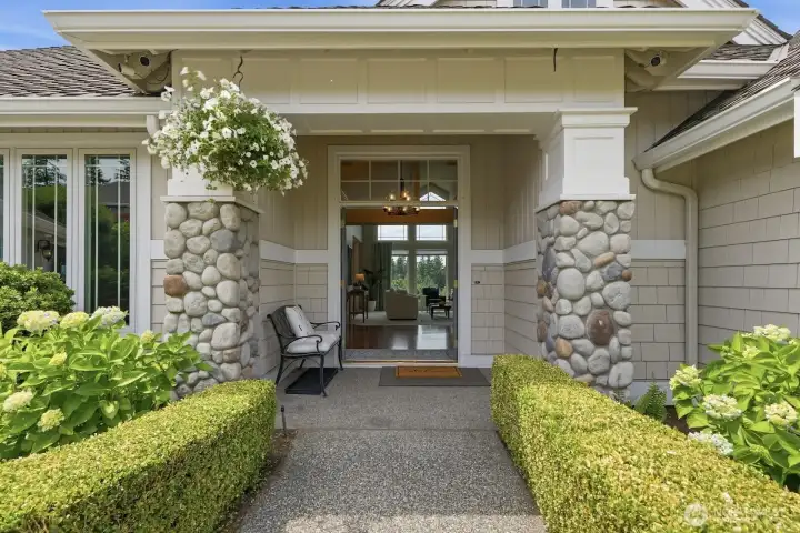 Entry with covered porch surrounded by mature landscape