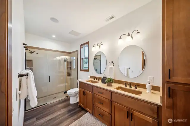 Gorgeous primary bedroom ensuite boasts a double vanity, custom cabinetry, and luxurious Onyx stone shower.