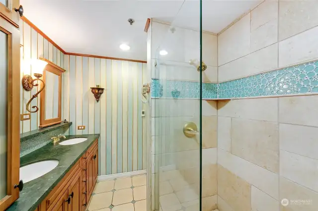 Bathroom has tile floor and double shower with tile surround to the ceiling.