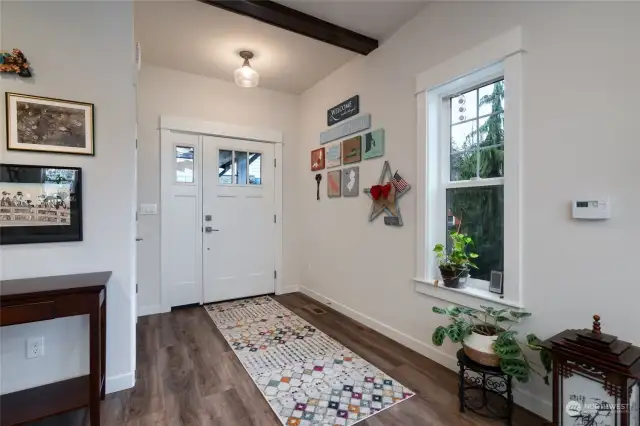 Front entrance into great room with LVP plank flooring and beamed detailing on the ceilings.