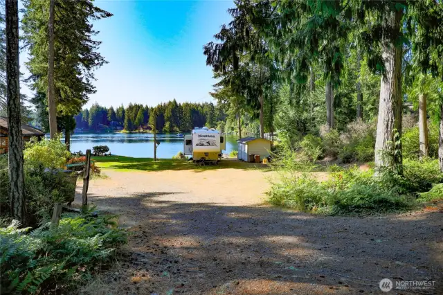 From the driveway showing your level .34-acre lot, RV, shed and beautiful view of the lake.