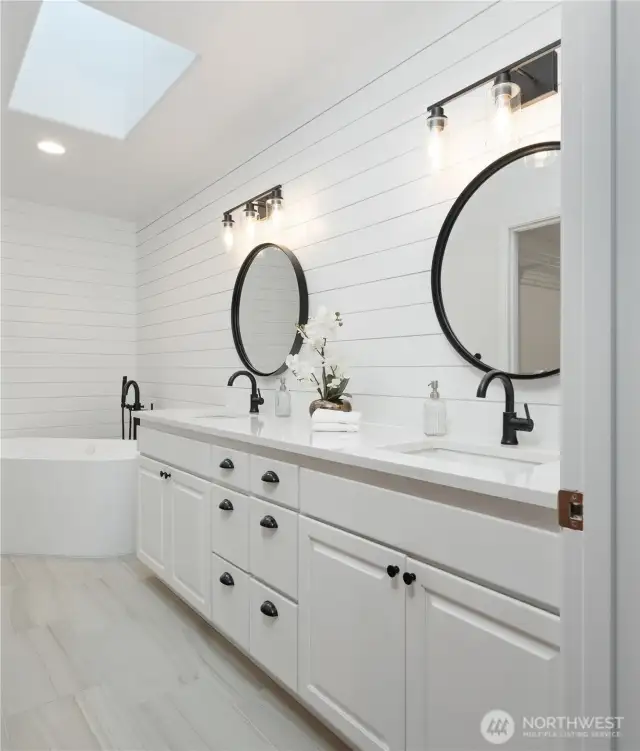 Primary bathroom featuring dual vanity, free-standing soaking tub, double headed shower and a skylight that bathes the space with natural light.
