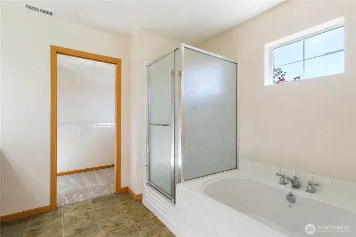Primary ensuite with soaking tub an door to walk in closet