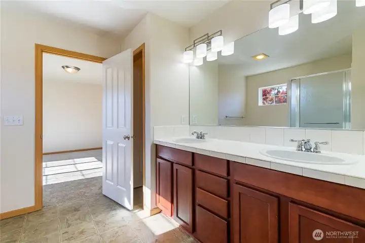 Primary ensuite with double sinks & linen closet behind bathroom door