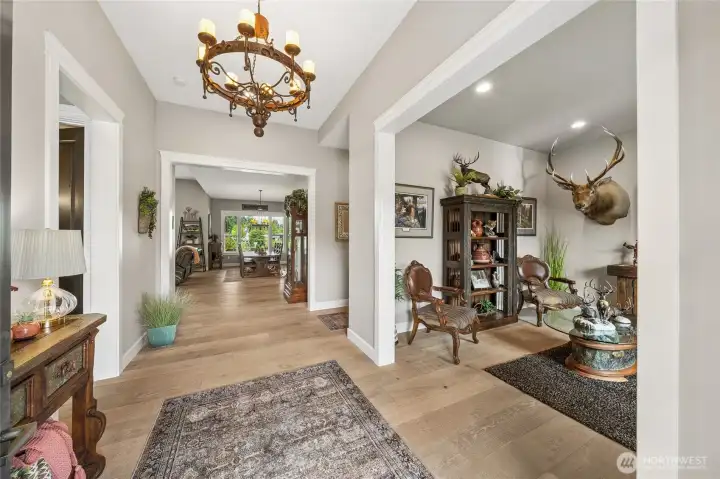 A grand entry foyer welcomes you with an elegant chandelier as its centerpiece, casting a warm glow over lovely White Oak flooring. A grand entry foyer welcomes you with an elegant chandelier as its centerpiece, casting a warm glow over lovely White Oak flooring.