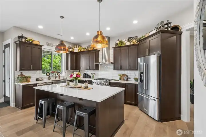 The well-appointed culinary kitchen shines with high-end stainless steel appliances, sleek slab countertops, copper lighting, crisp white subway tile; perfectly balanced for everyday functionality with elevated style. The well-appointed culinary kitchen shines with high-end stainless steel appliances, sleek slab countertops, copper lighting, crisp white subway tile; perfectly balanced for everyday functionality with elevated style.